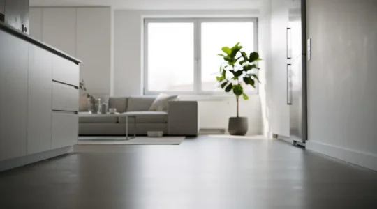 Suelo continuo de microcemento sin juntas que unifica visualmente la cocina y el salón de una vivienda moderna