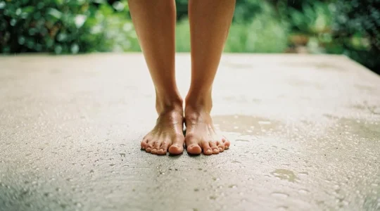 Persona descalza sobre una terraza con suelo poroso seco justo despues de la lluvia, sin charcos visibles